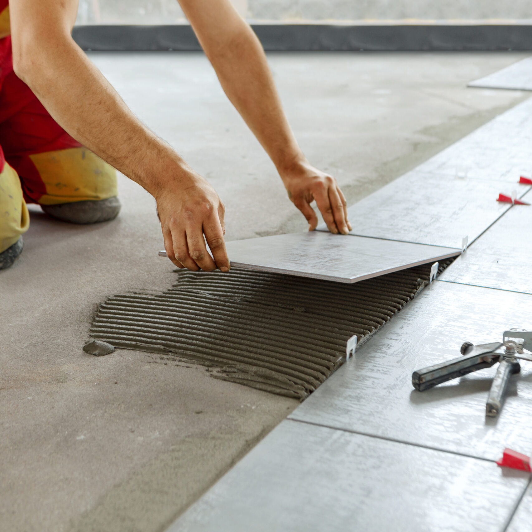 Ceramic Tiles. Tiler placing ceramic wall tile in position over